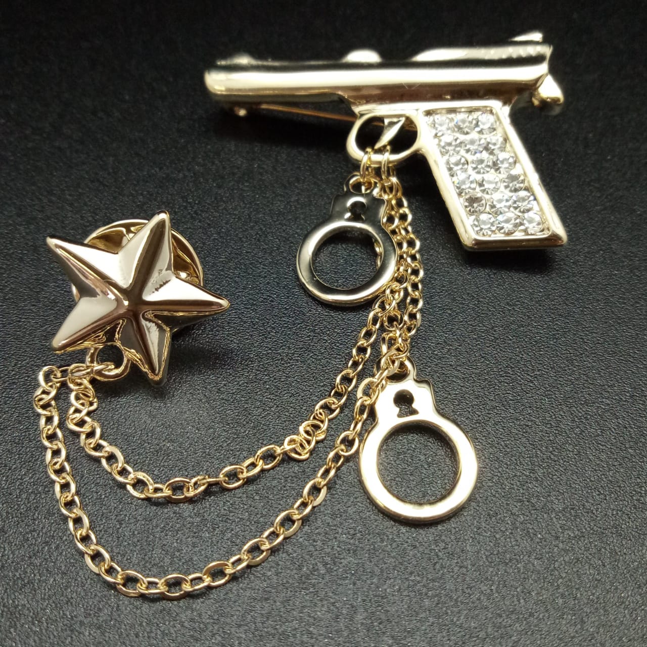 картинка Брошь 10 см золотой Пистолет, наручники и звезда на цепочке от магазина El Corazon